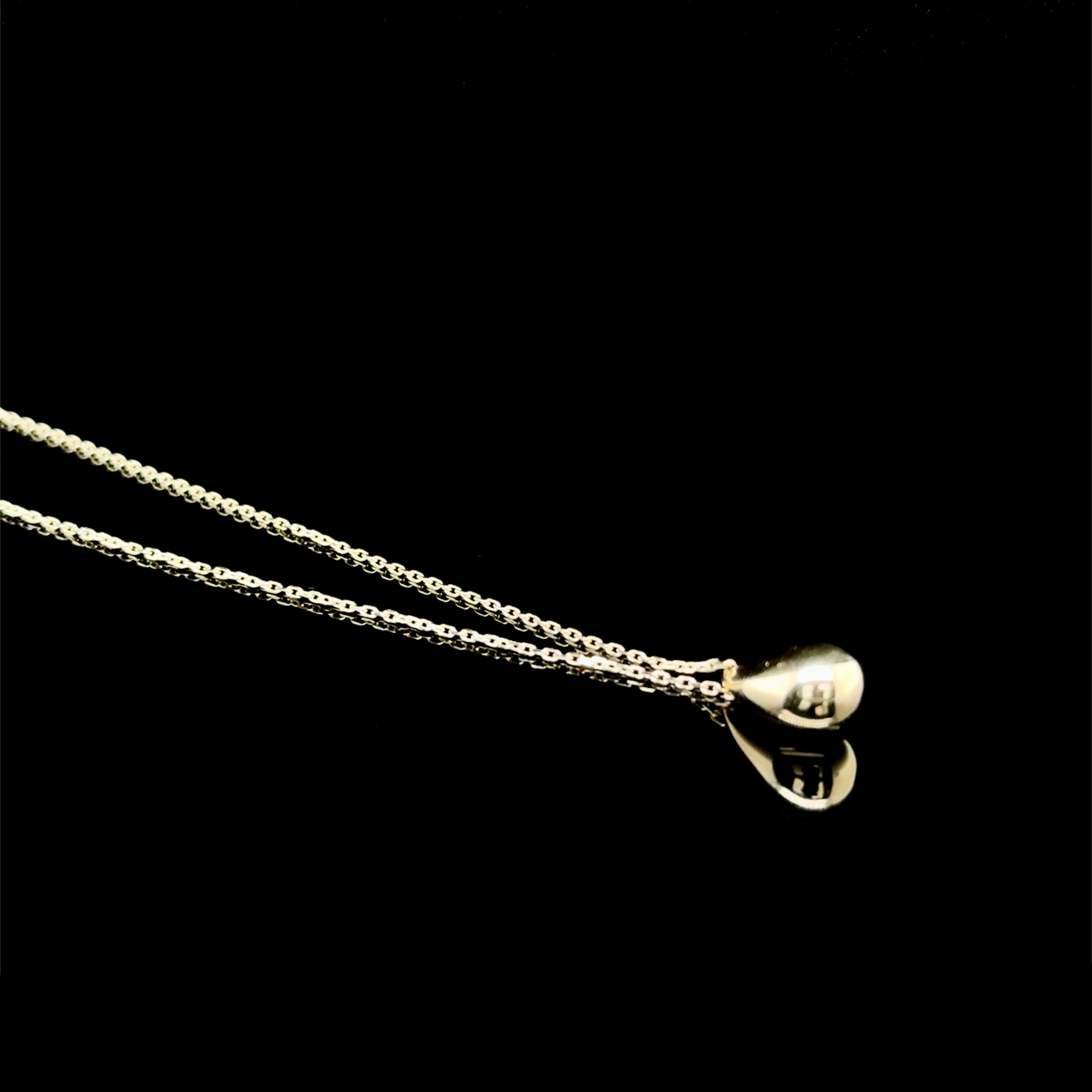 Gold teardrop necklace on a black background.